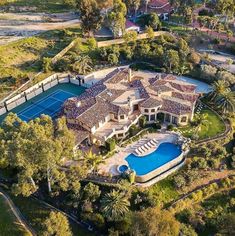 an aerial view of a home with a tennis court and pool in the foreground