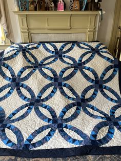 a blue and white quilt sitting on top of a bed next to a fire place