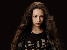 a young woman with long hair standing in front of a black background and looking at the camera