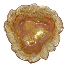 a yellow glass bowl with leaves on the bottom and center piece in the shape of a heart