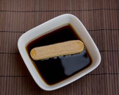 a small white bowl filled with sauce and a piece of bread