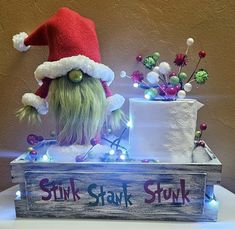 a stuffed animal wearing a santa claus hat sitting on top of a wooden box with lights around it