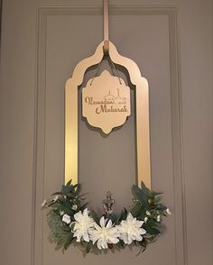 the front door is decorated with white flowers and greenery, along with a plaque that reads