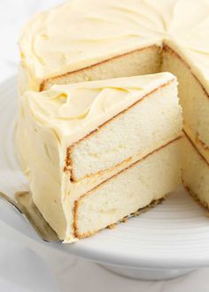 a white cake on a plate with a slice cut out of it's side