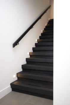 a set of black stairs leading up to a white wall