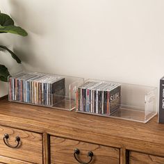 a wooden dresser with two clear acrylic cases on top and dvd's in the bottom