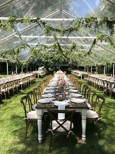 an outdoor tent set up with tables and chairs for a formal dinner or party in the grass