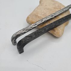 two knives sitting next to each other on top of a rock