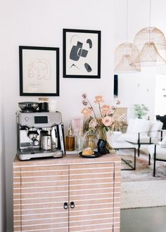 a coffee machine sitting on top of a wooden cabinet next to a vase filled with flowers