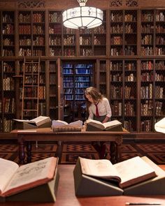 a woman sitting at a table in front of a book shelf filled with lots of books