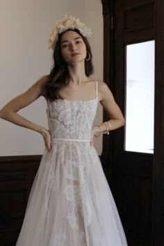 a woman in a white dress standing next to a door with her hands on her hips