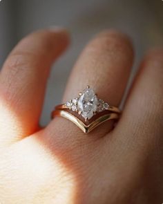 a woman's hand with a gold and white diamond ring on top of her finger