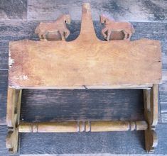 an old wooden bench with two horses on it's back and the seat is made out of wood