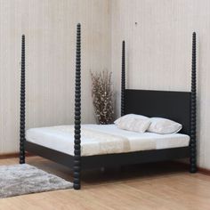 a bed with four posts in a bedroom next to a rug and wooden flooring