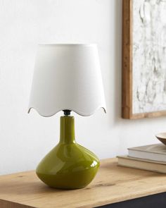 a green lamp sitting on top of a wooden table