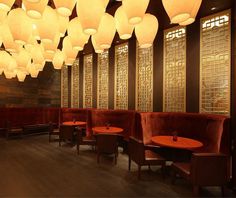 an empty restaurant with red booths and lanterns hanging from the ceiling above it's tables