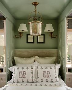 a bedroom with green walls, white bedding and two lamps on either side of the bed