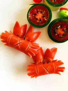 some plastic toys are laying on a white surface with tomatoes and other vegetables in the background