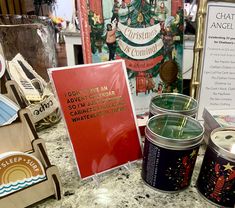 there are many items on the counter in this store that include candles, tins and magnets