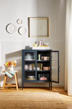 a room with a rug, table and shelves in it that have items on them