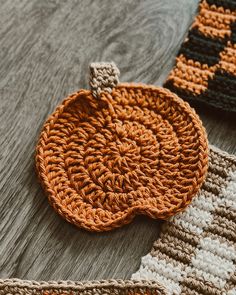 two crocheted pumpkins sitting on top of a wooden table