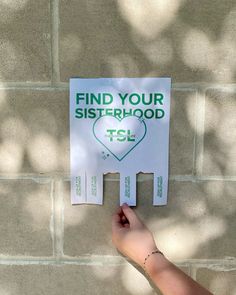 a hand holding up a sign that says find your sisterhood tsl on it