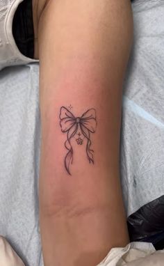 a small bow tattoo on the arm