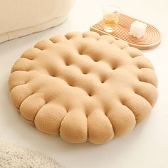 a round shaped cushion sitting on top of a white table next to a wooden tray