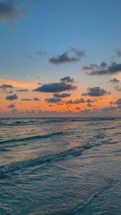 the sun is setting over the ocean with clouds in the sky and waves crashing on the beach