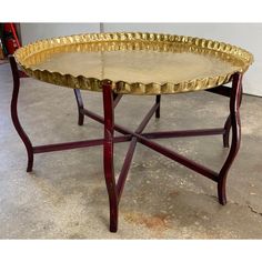 a gold tray sitting on top of a wooden table next to a red metal stand