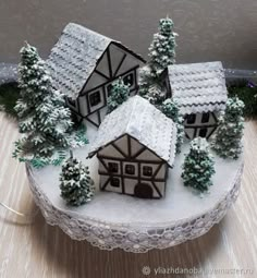 there is a cake that looks like a house in the snow with trees around it