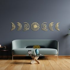 a living room with a couch, coffee table and three metal moon phases on the wall