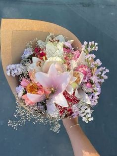 a bouquet of flowers is being held by someone's hand on the water surface