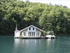 a house sitting on top of a lake surrounded by trees