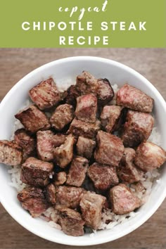 a white bowl filled with meat and rice on top of a wooden table next to a fork