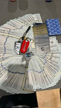 a bunch of money sitting on top of a table next to a red car key