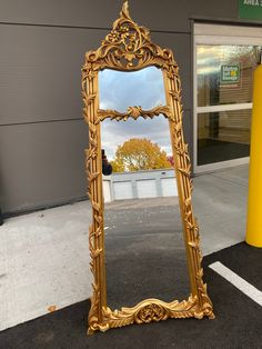 an ornate gold mirror sitting in the middle of a parking lot