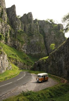 an orange and white van driving down a mountain road