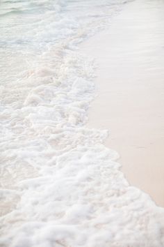 two people walking on the beach with surfboards