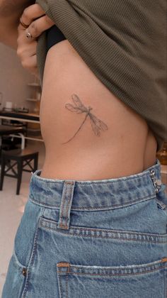 a woman's stomach with a small dragonfly tattoo on it