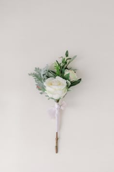 a boutonniere with white flowers and greenery is hanging on the wall