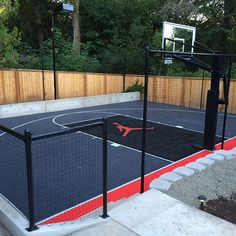 an outdoor basketball court in the middle of a fenced in area with a basketball hoop