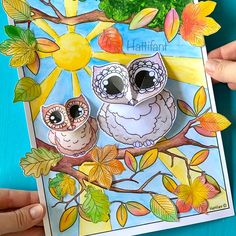 two owls sitting on a tree branch in front of a blue background with autumn leaves