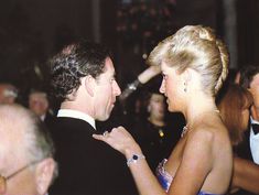 a man in a tuxedo is talking to a woman wearing a blue dress