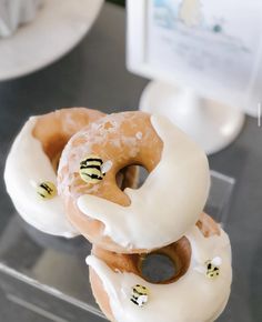 there are three donuts with white frosting and honeybees on them in a display case