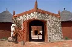 the entrance to an adobe style building with thatched roof and round doorways on either side