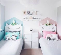 two white beds with pink and blue covers in a room decorated with bunting garlands