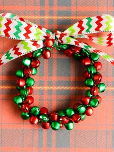 a close up of a christmas wreath on a table with red, green and white ribbon