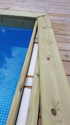 an empty swimming pool with blue water and wooden planks on the bottom edge, next to a deck