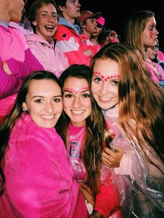 three girls in pink are posing for the camera with their faces painted like animals and people behind them